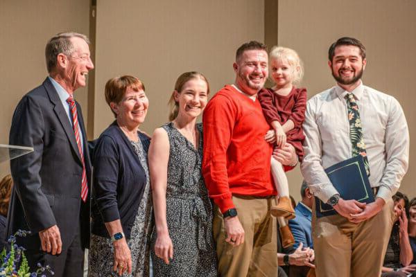 The family of Kelly McGaughey Roseberry joins 澳门线上赌博平台大学 physical therapy student Ryan McGinniss for a photo.